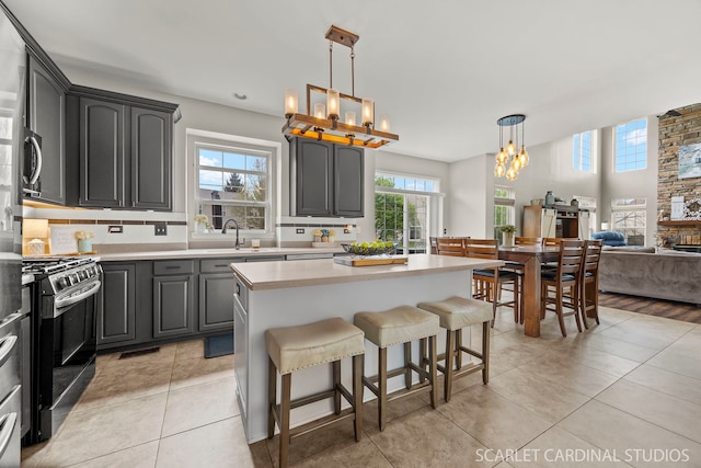 kitchen featuring a chandelier, stainless steel gas range oven, light countertops, a kitchen island, and light tile patterned floors