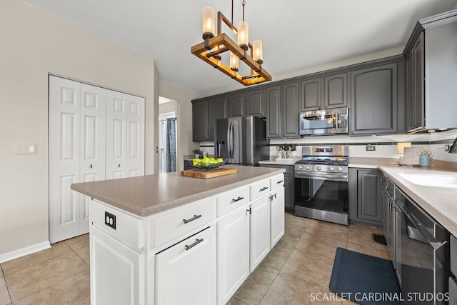 kitchen with appliances with stainless steel finishes, a chandelier, light tile patterned flooring, a sink, and white cabinetry