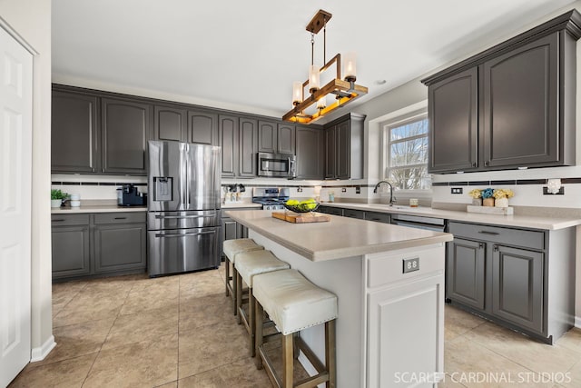 kitchen featuring appliances with stainless steel finishes, light countertops, a center island, a kitchen breakfast bar, and backsplash