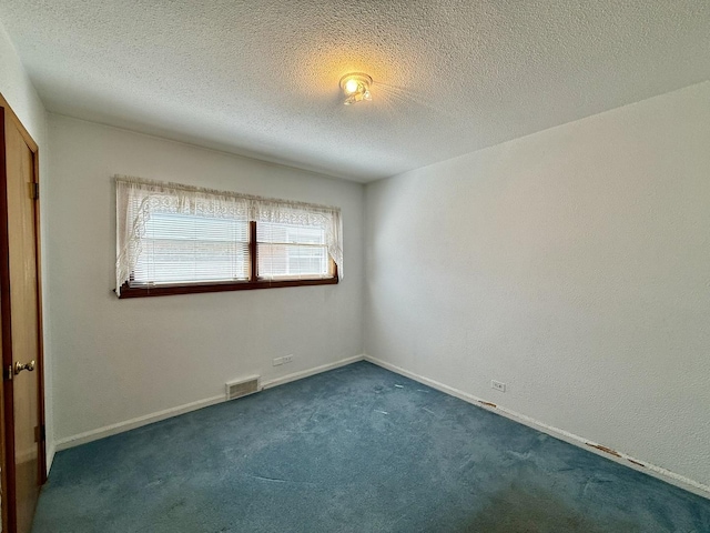 unfurnished bedroom with dark colored carpet, visible vents, a textured ceiling, and baseboards