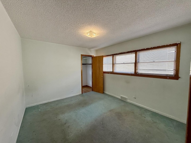 unfurnished bedroom with a closet, baseboards, visible vents, carpet, and a textured ceiling