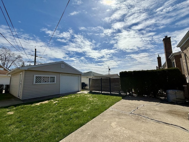 view of yard with a garage, driveway, an outdoor structure, and fence