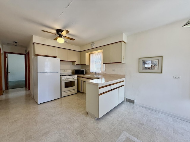 kitchen featuring a sink, light countertops, ceiling fan, white appliances, and a peninsula