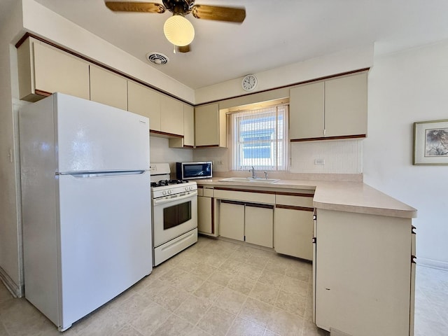 kitchen featuring visible vents, a sink, light countertops, white appliances, and cream cabinetry