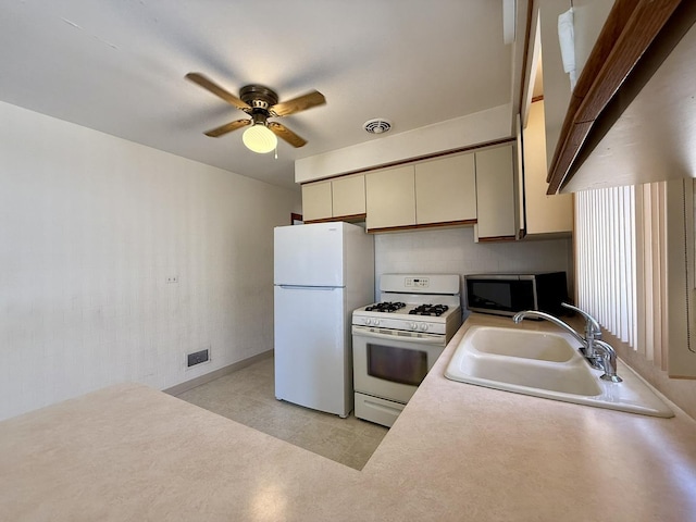 kitchen with white appliances, a ceiling fan, cream cabinetry, visible vents, and a sink