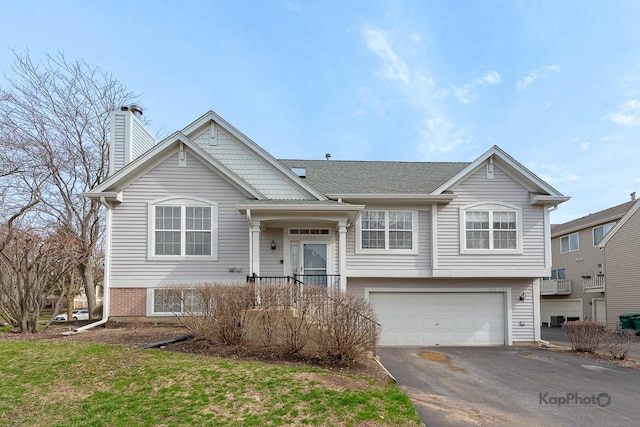 view of front of house with aphalt driveway, a chimney, and an attached garage