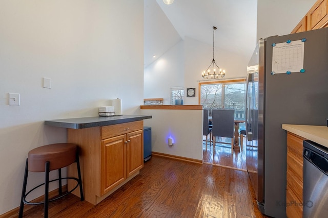 kitchen with hanging light fixtures, dark wood-style flooring, appliances with stainless steel finishes, a chandelier, and high vaulted ceiling