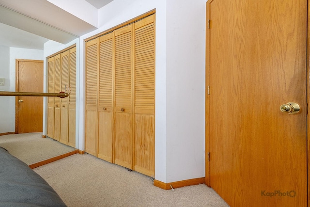 corridor with baseboards and light colored carpet