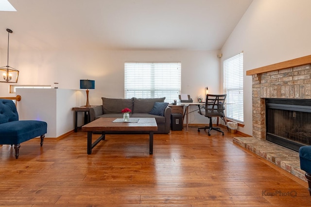 living area with baseboards, hardwood / wood-style floors, a fireplace, and lofted ceiling