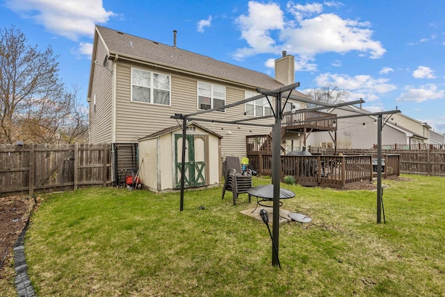 back of property with a storage unit, a fenced backyard, an outbuilding, and a chimney