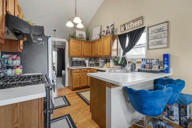 kitchen with a sink, high vaulted ceiling, stainless steel microwave, a peninsula, and gas range oven