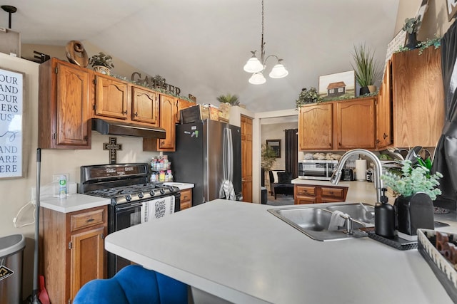 kitchen with freestanding refrigerator, a peninsula, under cabinet range hood, a sink, and black gas range oven