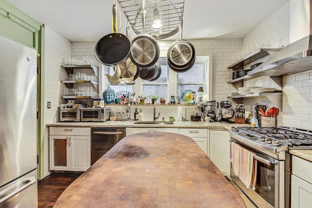 kitchen with stainless steel appliances, wood counters, a sink, and open shelves