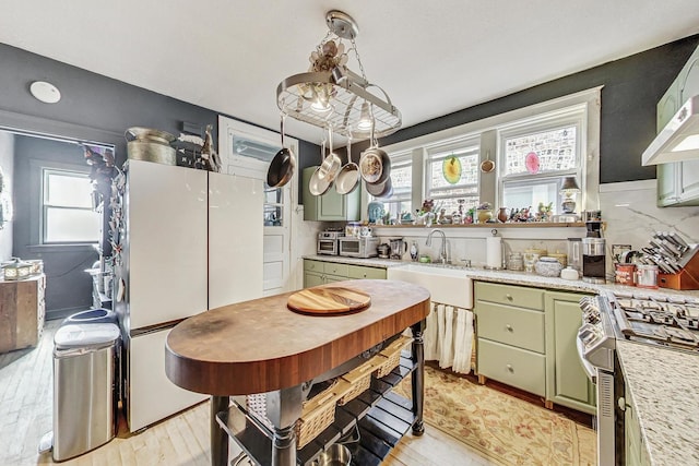 kitchen with green cabinets, light countertops, a sink, and a healthy amount of sunlight