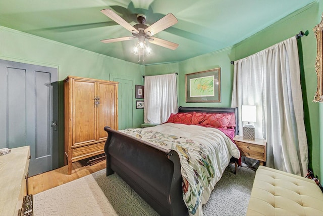 bedroom with light wood-style flooring, crown molding, and a ceiling fan