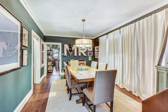 dining room with a chandelier, crown molding, wood finished floors, and baseboards