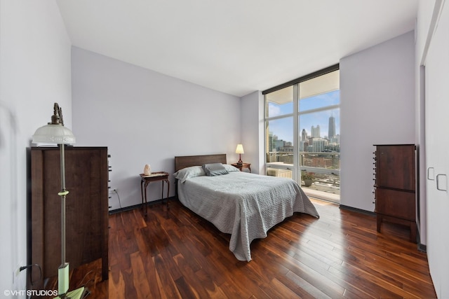 bedroom featuring a wall of windows, wood finished floors, and a city view