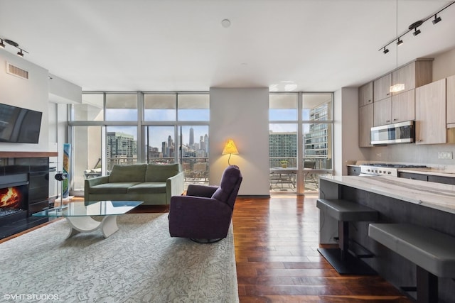 living area featuring visible vents, a wall of windows, a view of city, a tile fireplace, and dark wood-style floors