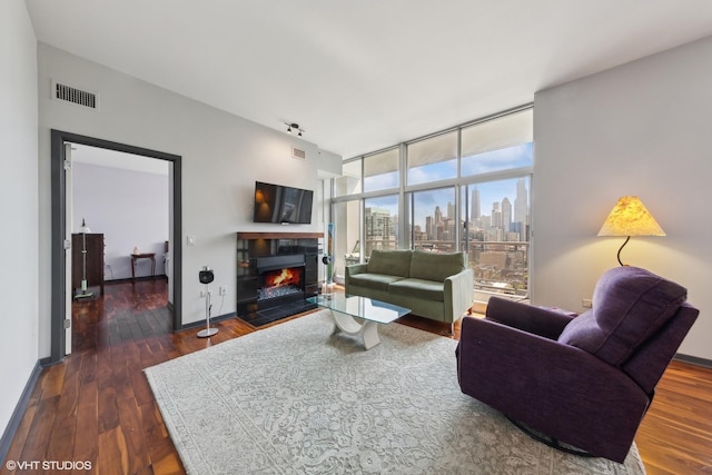 living room with visible vents, a wall of windows, wood finished floors, and baseboards