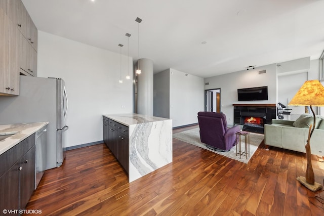 kitchen with a fireplace, light stone countertops, dark wood finished floors, and appliances with stainless steel finishes