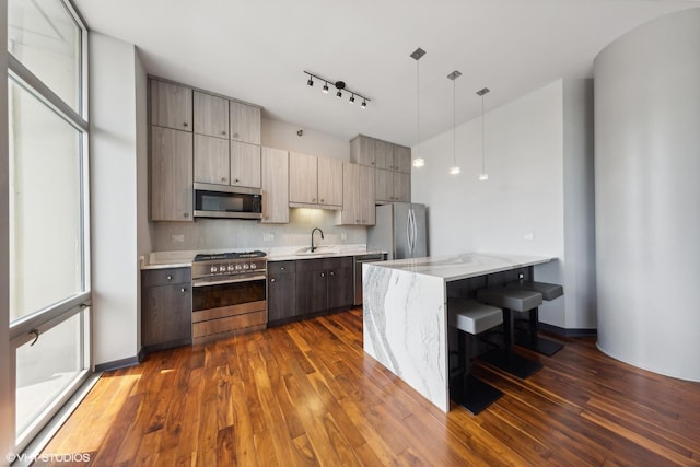 kitchen with light stone countertops, dark wood-type flooring, tasteful backsplash, appliances with stainless steel finishes, and a sink