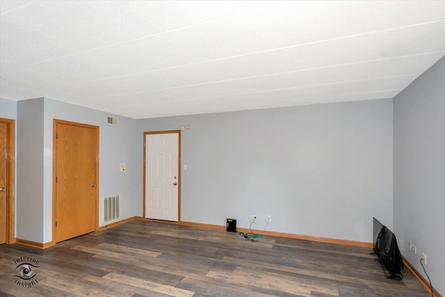 unfurnished room featuring baseboards, visible vents, and wood finished floors
