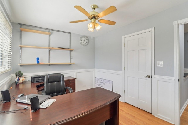 office with light wood-style flooring, a ceiling fan, and wainscoting