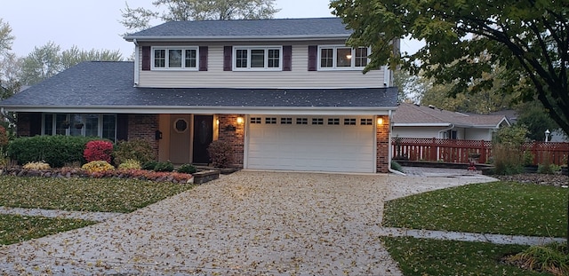 traditional home with brick siding, fence, a garage, and driveway