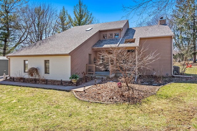 rear view of house featuring a shingled roof, a chimney, a lawn, and covered porch