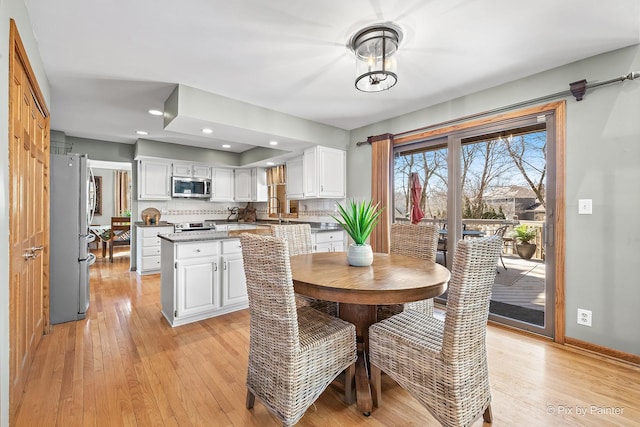 dining area featuring baseboards, light wood finished floors, a chandelier, and recessed lighting