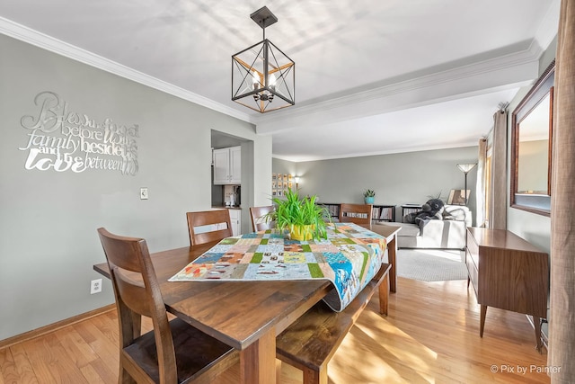 dining room featuring light wood-style flooring, a chandelier, baseboards, and ornamental molding