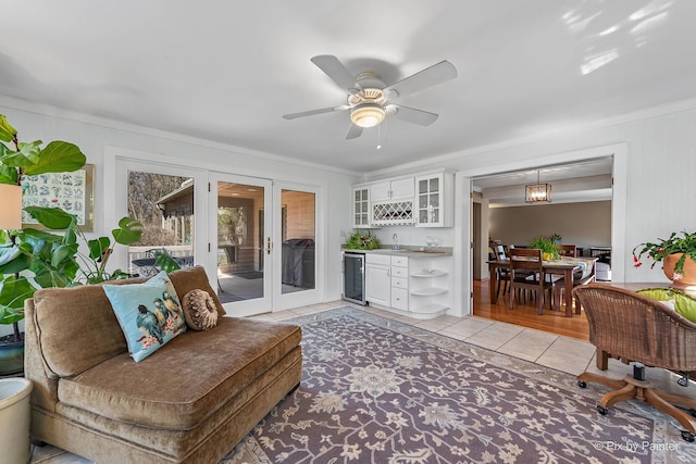living area with ceiling fan, light tile patterned floors, wet bar, wine cooler, and french doors