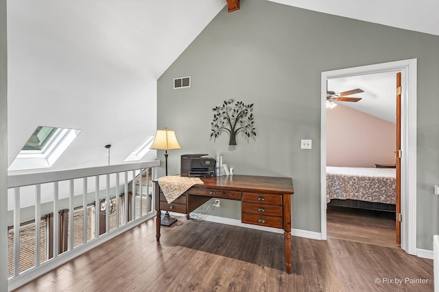 office area with visible vents, baseboards, vaulted ceiling with skylight, a ceiling fan, and wood finished floors