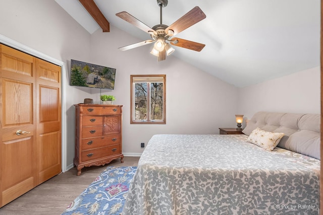 bedroom featuring baseboards, wood finished floors, lofted ceiling with beams, and a ceiling fan