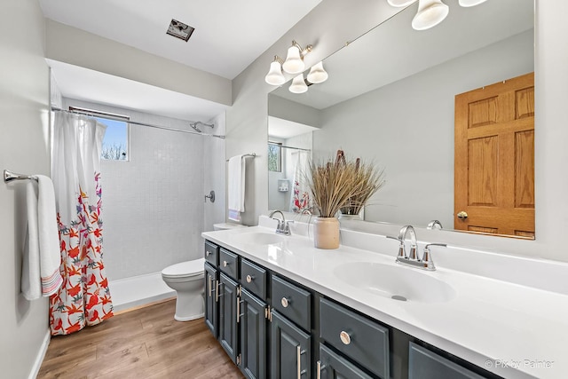 full bath featuring a sink, toilet, double vanity, and wood finished floors