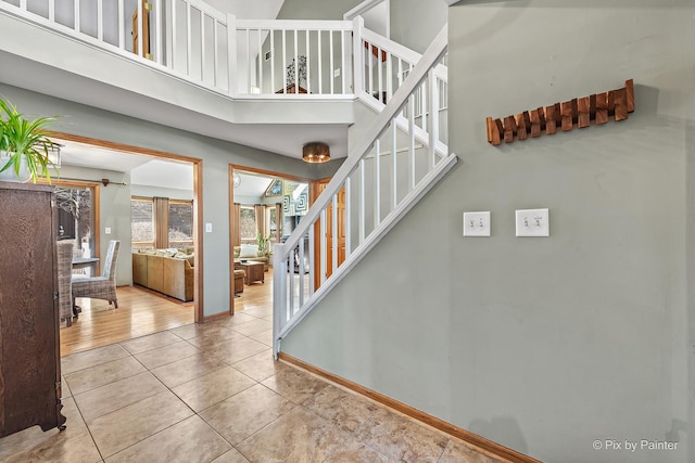 stairway featuring tile patterned floors, a towering ceiling, and baseboards