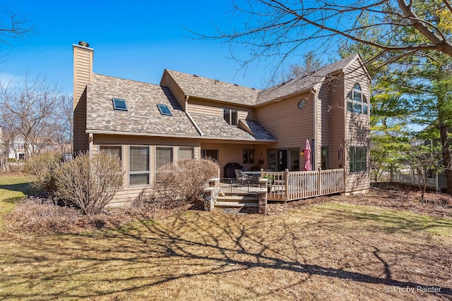 back of house with a wooden deck, a shingled roof, and a chimney