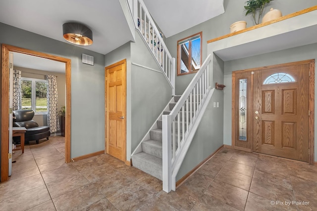 foyer with tile patterned floors, baseboards, visible vents, and stairs