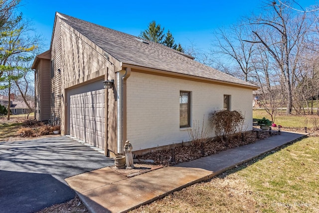 view of home's exterior with brick siding, a garage, driveway, and roof with shingles