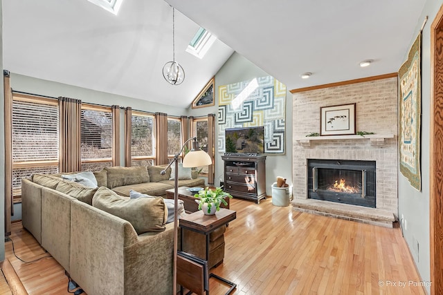 living room with a chandelier, a brick fireplace, a skylight, high vaulted ceiling, and hardwood / wood-style flooring