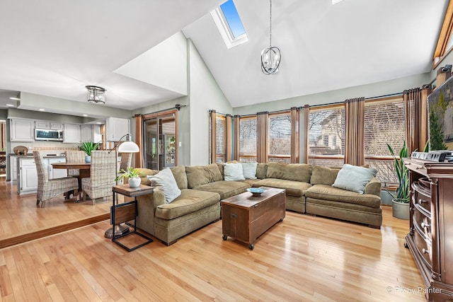 living area featuring a skylight, high vaulted ceiling, and light wood-style floors