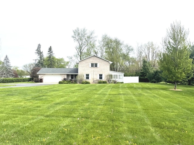 rear view of property featuring an attached garage, a yard, and aphalt driveway