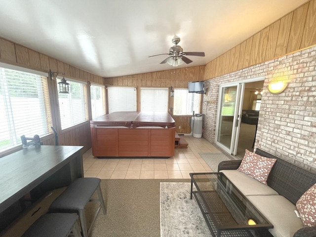 living area with light tile patterned floors, a ceiling fan, vaulted ceiling, and brick wall