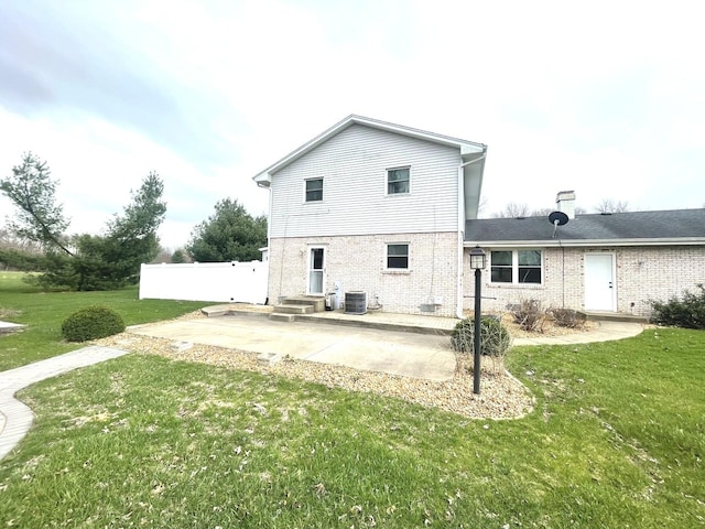 rear view of property featuring fence, cooling unit, a patio, brick siding, and a yard