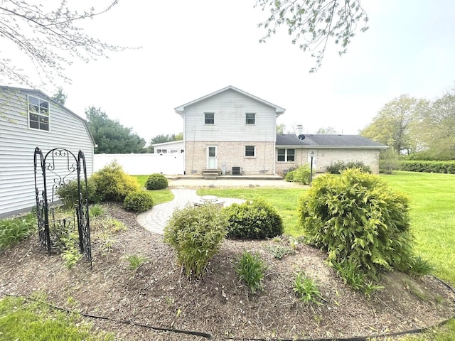 back of house featuring a lawn, brick siding, fence, and a patio area