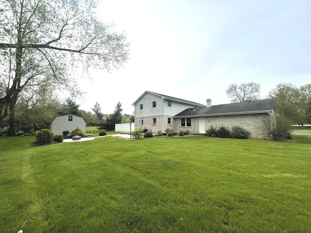 rear view of property featuring a lawn, an outbuilding, a chimney, and brick siding