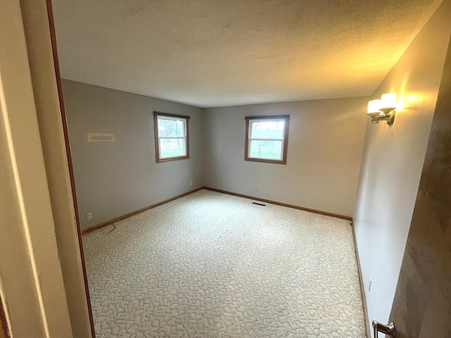 spare room featuring baseboards, carpet, and a textured ceiling