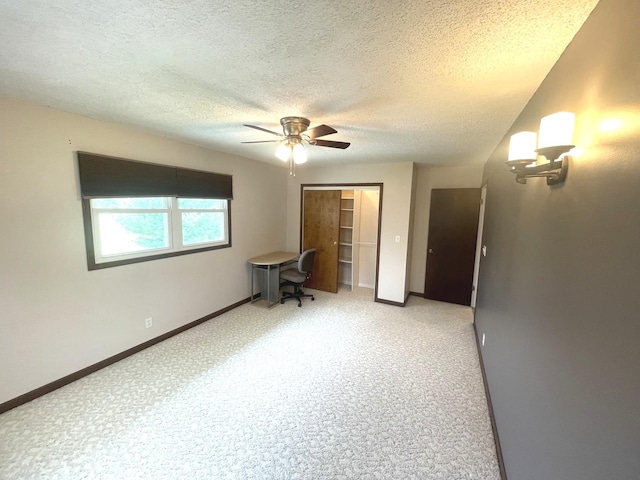 unfurnished bedroom featuring ceiling fan, a textured ceiling, baseboards, a closet, and carpet flooring