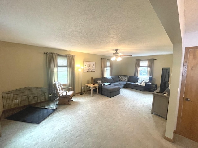 living room featuring a ceiling fan, a textured ceiling, light carpet, and baseboards