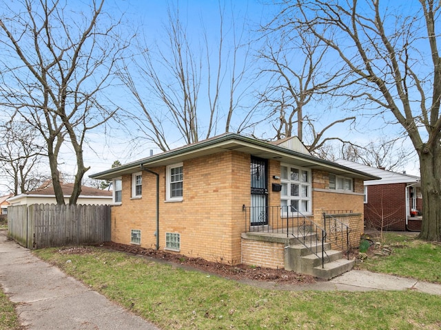 view of front of house featuring a front yard, brick siding, and fence